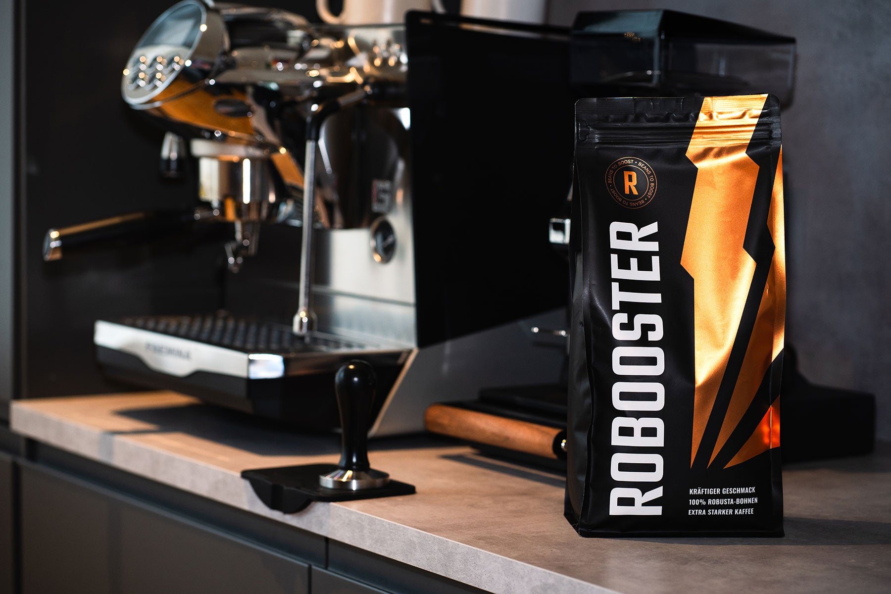 Robooster Kaffee in Barista-Umgebung neben moderner Kaffeemaschine.